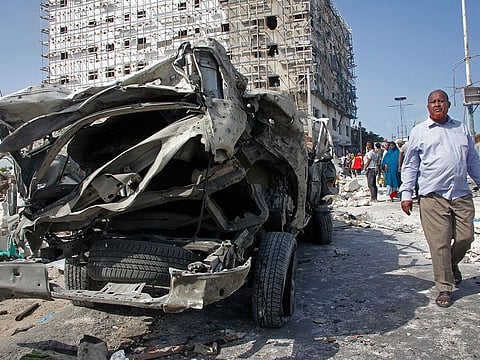 A man walks past the wreckage of an official vehicle that was destroyed in a bomb attack in the capital Mogadishu, Somalia, Saturday, June 15, 2019.