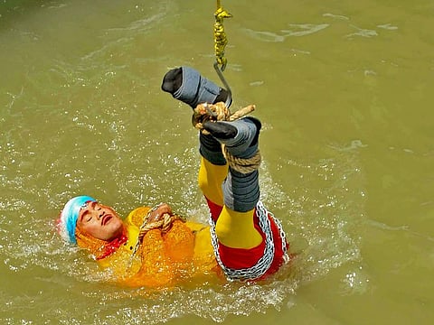Indian stuntman Chanchal Lahiri, known by his stage name "Jadugar Mandrake", is lowered into the Ganges river, while tied up with steel chains and ropes, in Kolkata. 