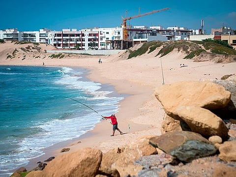 A Moroccan man fishes on a beach in the city of Mohammedia on May 22, 2019. A report from the United Nations Environment Program (UNEP) on the overexploitation of sand in the world points out the role of "sand mafias" in the loss of Moroccan beaches, amidst coastal urbanization. 