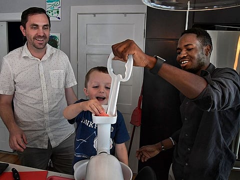 Joe McGill and Dieudonne Kazzembe (right) with help from 4-year-old Jack McGill, grind meat for a Father’s Day cookout last Sunday.