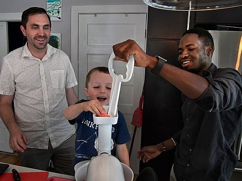 Joe McGill and Dieudonne Kazzembe (right) with help from 4-year-old Jack McGill, grind meat for a Father’s Day cookout last Sunday.