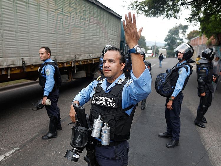 Riot police allow traffic through during a day of protests in Tegucigalpa, Honduras, Friday, June 21, 2019. 