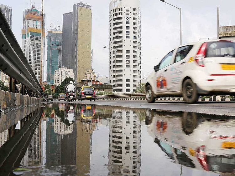 Vehicles drive past buildings under construction in Mumbai