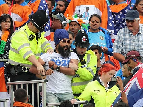 A handcuffed Sikh spectator reacts as he is taken away by cops during the World Cup semi-final match between India and New Zealand at Old Trafford in Manchester, on July 9, 2019. 