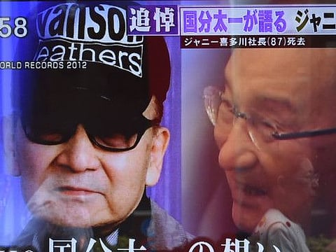 A woman walks past a roadside television screen reporting the death of Johnny Kitagawa, founder of Japanese talent agency Johnny & Associates Inc., in Tokyo on July 10, 2019.  Japan's leading boyband star-maker Johnny Kitagawa, who built an entertainment empire and broke records with his acts, has died of a stroke on July 9, his company said. He was 87. / AFP / Kazuhiro NOGI