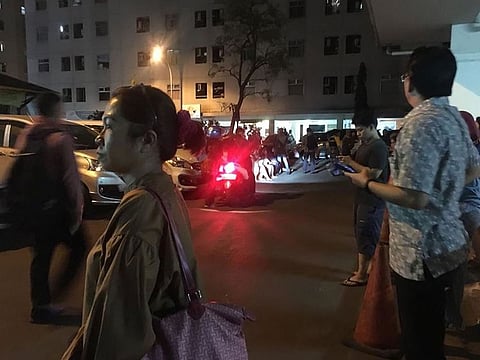 Resident stand outside an apartment block after a strong earthquake hit the area around Jakarta on August 2, 2019. 