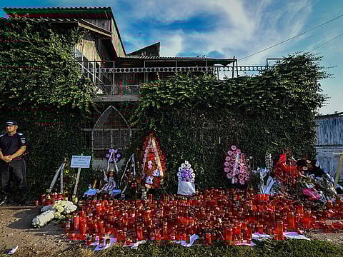 Romanian gendarmes stand guard next to flowers and candles displayed by locals at the gates of the home of Gheorghe Dinca alleged killer of Alexandra, 15, who has being murdered after she telephoned threetimes to report her own kidnapping and Luiza, 18, in Caracal city on August 2, 2019.  Romania's Interior Minister resigned on July 30 amid a wave of public revulsion over a murder case in which police failed to react in time to save a teenage girl. 