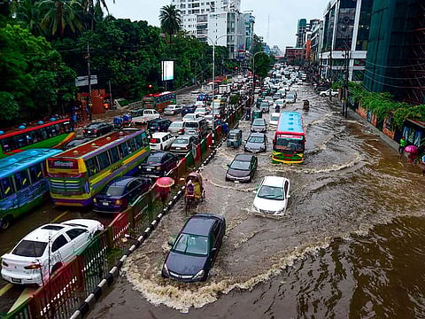  Bangladeshi drivers make their way through heavy rainfall at a water-logged street during the monsoon season in Dhaka.