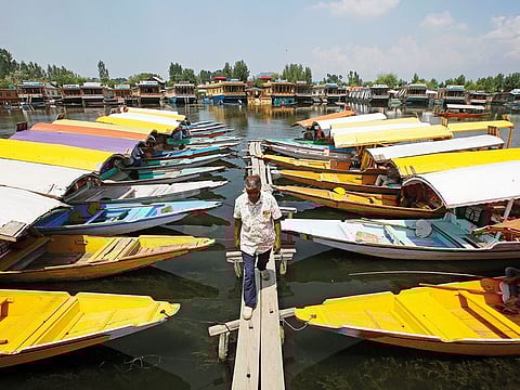 A boatman walks past the parked 'Shikaras' or boats for tourists on the banks of Dal Lake in Srinagar.