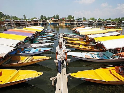 A boatman walks past the parked Kashmiri 'shikaras' or little boats for tourists on the banks of the famous Dal Lake in Srinagar