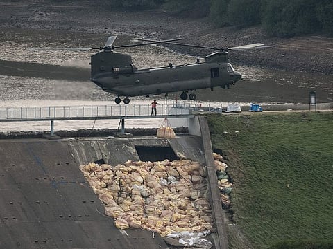 An RAF Chinook helicopter drops more bags of aggregate on the damaged section of spillway of the Toddbrook Reservoir dam above the town of Whaley Bridge in northern England on August 4, 2019.