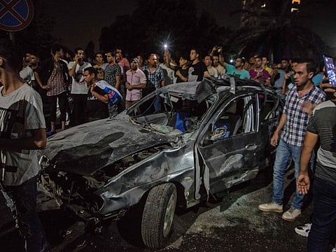 Onlookers gather around a charred car, following an accident just before midnight on August 4, 2019, outside the National Cancer Institute in the Egyptian capital Cairo. 