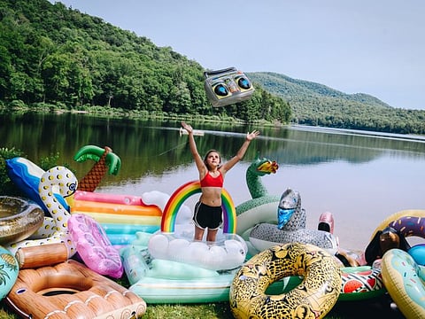 Penny Glasgow with a pile of floats at Sand Lake in the Adirondacks near Hadley, N.Y., on July 21, 2019. Floaties that look like food, animals and mythical creatures have become essential for status-seeking Instagrammers. (Nina Westervelt/The New York Times)
