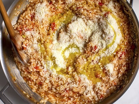 Tomato risotto gets a drizzle of olive oil and a dusting of pecorino cheese just before serving in New York, July 29, 2019. Food styled by Iah Pinkney. (Andrew Scrivani/The New York Times)