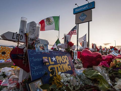 People pray and pay their respects at the makeshift memorial for victims of the shooting that left a total of 22 people dead at the Cielo Vista Mall WalMart (background) in El Paso, Texas, on August 6, 2019. 