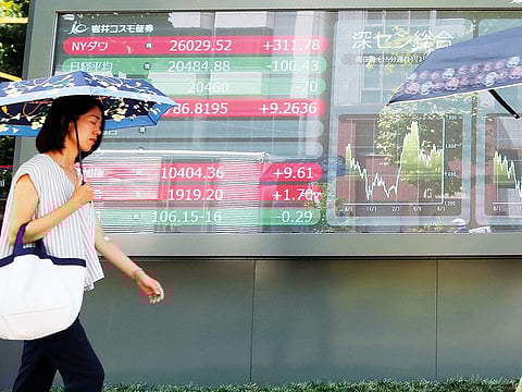 People walk by an electronic stock board of a securities firm in Tokyo, on Wednesday, August 7, 2019. 