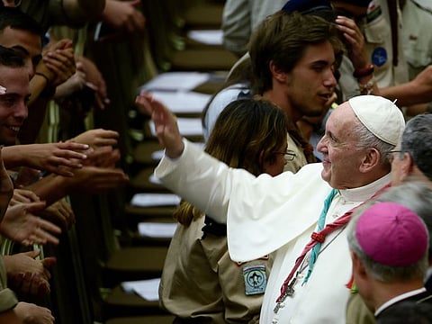 Pope Francis waves to faithful and wears a scout scarf given by a participant, during the Euromoot meeting (Federation of European Scouting) in the Paul VI hall at the Vatican, on August 3, 2019.