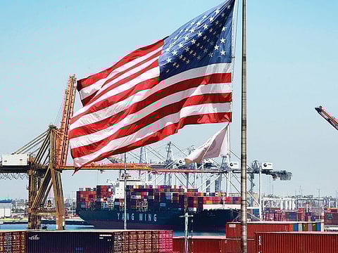 The US flag flies over a ship unloading its cargo from Asia, at the Port of Long Beach, California. 