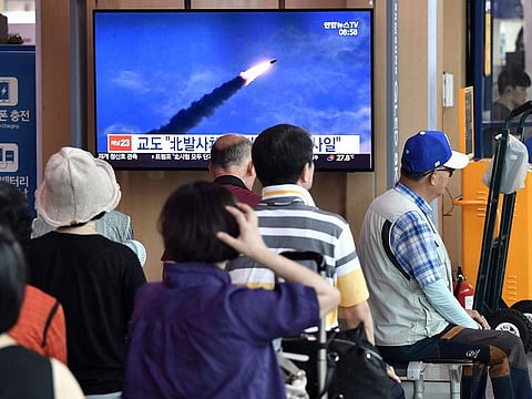 People watch a television news screen showing file footage of North Korea's missile launch, at a railway station in Seoul. 
