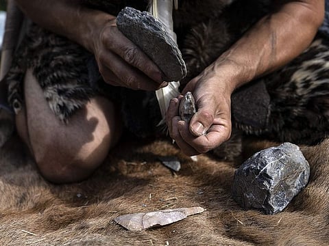 Guido Camia dressed as a Neanderthal Cave man works on a flint ax in a wood near Chianale, in the Italian Alps, near the French border.