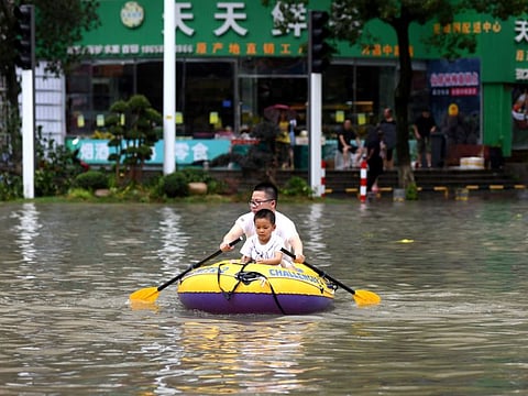 A man rows an inflatable kayak carrying a boy on a flooded street after Typhoon Lekima hit Wenling, Zhejiang province, China August 10, 2019. 