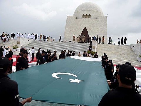 Pakistani police with the Special Security Unit (SSU) hold a national flag in front of the mausoleum of founding father Quaid-e-Azam Mohammad Ali Jinnah during Independence Day celebrations in Karachi