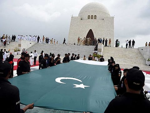 Pakistani police with the Special Security Unit (SSU) hold a national flag in front of the mausoleum of founding father Quaid-e-Azam Mohammad Ali Jinnah during Independence Day celebrations in Karachi