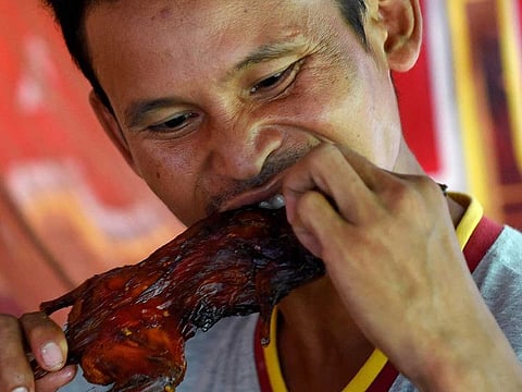 A man eating a grilled rat at a stall in Battambang province.
