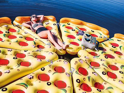 Penny Glasgow with a pile of floats at Sand Lake in the Adirondacks near Hadley, N.Y., on July 21, 2019. Floaties that look like food, animals and mythical creatures have become essential for status-seeking Instagrammers. (Nina Westervelt/The New York Times)