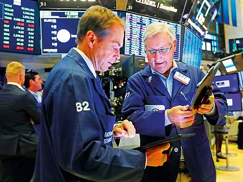 Traders Dudley Devine, left, and Christopher Fuchs work on the floor of the New York Stock Exchange.