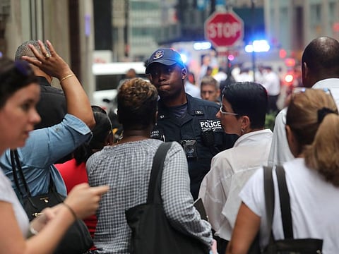 An anti-terror NYPD officer, center, listen to pleas from people trying to get past him to work, as police seal off area in the financial district around the the Fulton Street subway hub to investigate a suspicious item, Friday Aug. 16, 2019, in New York