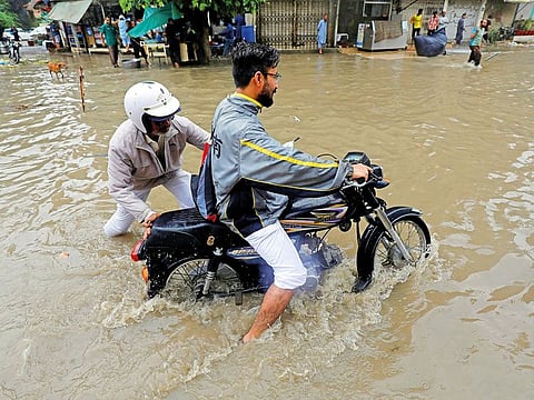 A traffic police officer helps a motorcyclist stuck in a ditch amid flooding in Karachi, last week. Officials say a clean-up drive in Karachi will tackle drainage problems in the city.