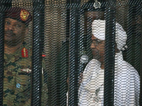 Sudan's deposed military ruler Omar al-Bashir stands in a defendant's cage during the opening of his corruption trial in Khartoum on August 19, 2019.