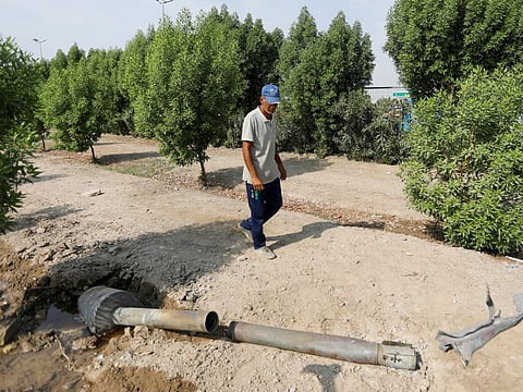 A man glances at a rocket that flew away from an Iraqi militia group's weapons depot after it caught fire, in Baghdad, Iraq, August 13, 2019. 