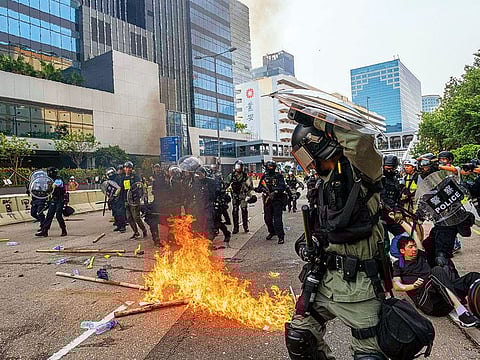 A fire breaks out as demonstrators and police officers in riot gear clash in the Kowloon Bay district of Hong Kong.