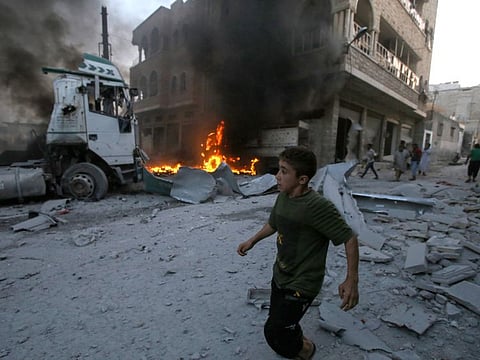 A young boy runs past a fire started in a building following a reported airstrike by Syrian regime forces in the area of Maaret al-Numan in Syria's northwestern Idlib province on August 28, 2019.