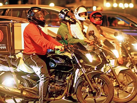 Delivery bikers patiently wait at a traffic signal.