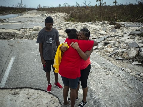 Brennamae Cooper, right, cries and hugs a friend after finding themselves walking in opposite directions, one escaping the destruction of Hurricane Dorian and the other on the way to search for her relatives, on a shattered road near the town of High Rock, Grand Bahama, Bahamas, Thursday Sept. 5, 2019.