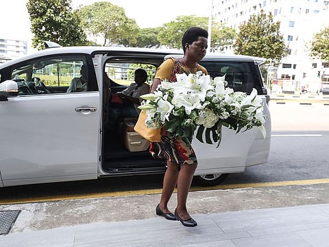 A visitor arrives with a wreath at the Singapore Casket funeral parlor building where the body of the late former president of Zimbabwe is being held on Saturday, Sept. 7, 2019, in Singapore. 