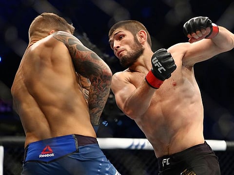 Russian UFC fighter Khabib Nurmagomedov, right, fights with UFC fighter Dustin Poirier, of Lafayette, La., during Lightweight title mixed martial arts bout at UFC 242, in Yas Mall in Abu Dhabi, United Arab Emirates, Saturday , Sept.7 2019.