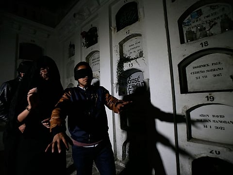 Blindfolded tourists walk through El Tejar cemetery in downtown Quito, Ecuador.
