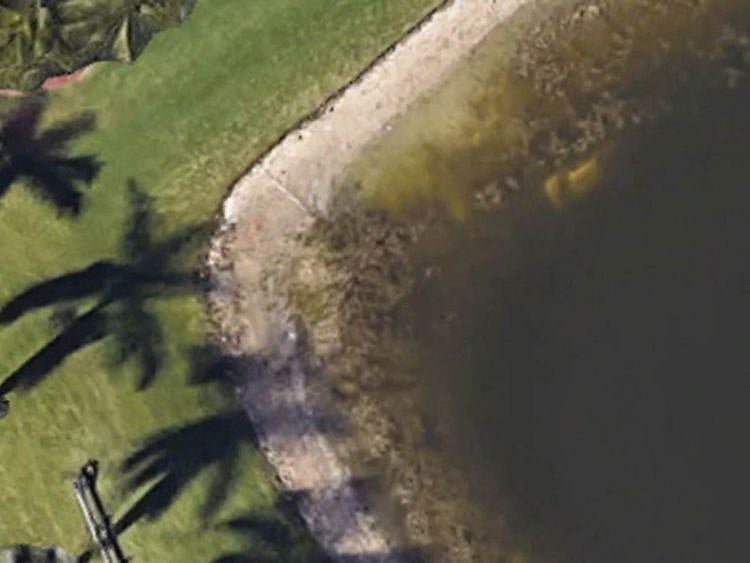 A car is shown submerged in a retention pond in Wellington