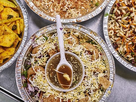 Plates of food, including fuchka, deep-fried semolina shells filled with potatoes and yellow split peas, and tamarind water for dipping, from Fuskahouse, a Bengali snack cart that opened in January, in New York, Aug. 23, 2019. The cart is one of two on the same patch of turf, both with virtually identical menus, headlined by fuchka, a Bengali snack that is kin to gol gappa in India’s north and pani puri in the west and south. (An Rong Xu/The New York Times)