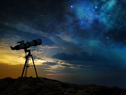 milky way at dawn and silhouette of a telescope