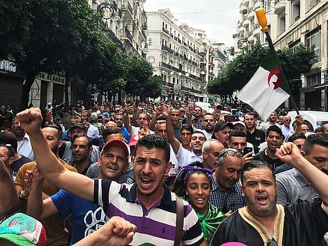 A demonstrator holds a placard that reads, 'throw the revolution into the street the people will take care', during a march in the capital Algiers to protest against the government, in Algeria, Friday, Sept. 13, 2019.