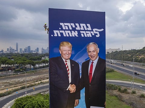 A worker hangs an election campaign billboard of the Likud party showing US President Donald Trump, left, and Israeli Prime Minister Benjamin Netanyahu in Tel Aviv. 