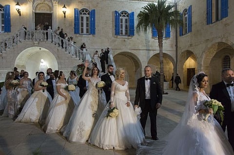 Brides and grooms line up to sign paperwork at a mass wedding of 34 couples at the Maronite Church in Bkerke, outside Beirut.
