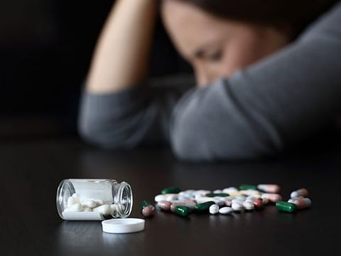 Depressed woman beside a lot of pills
