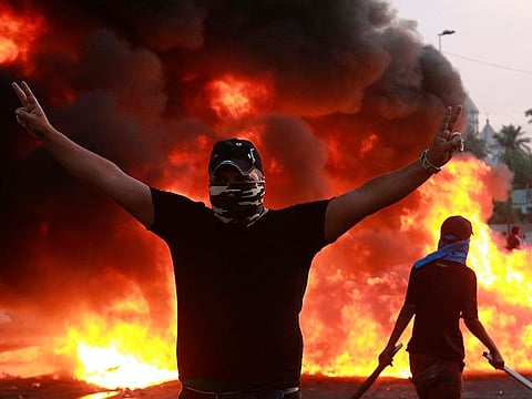 An anti-government protester flashes the victory sign during a demonstration in Baghdad, Iraq, Thursday, Oct. 3, 2019.