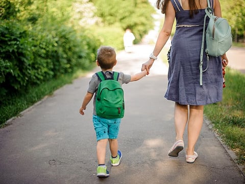 A mother walking down the street with a little son 